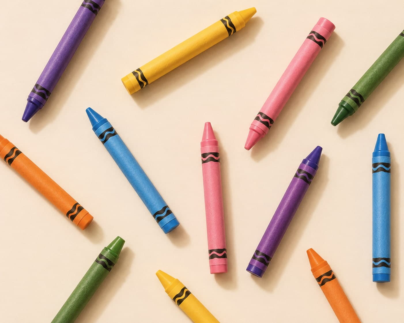 Colorful crayons in purple, gold, pink and green arranged on a cream background
