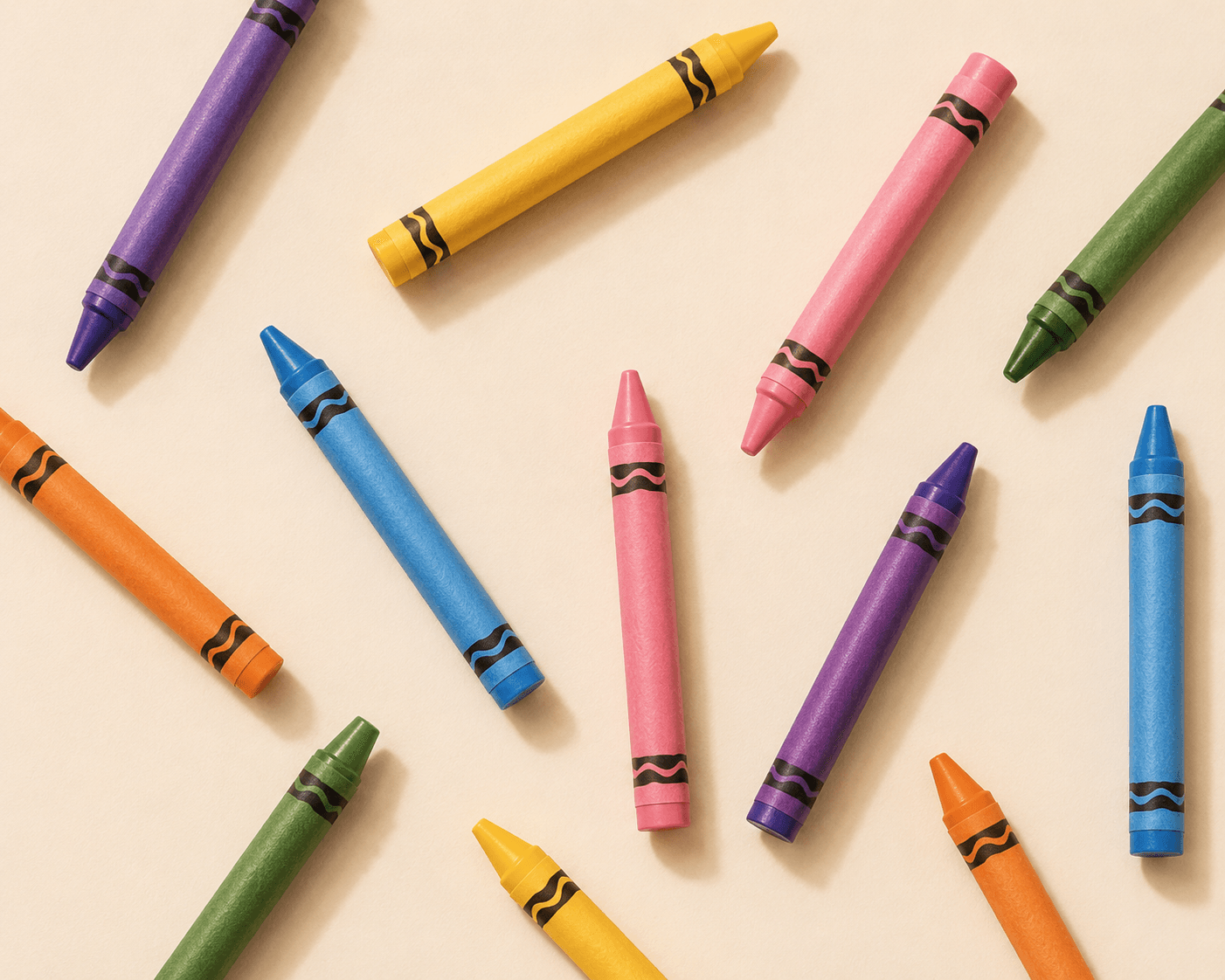 Colorful crayons in purple, gold, pink and green arranged on a cream background